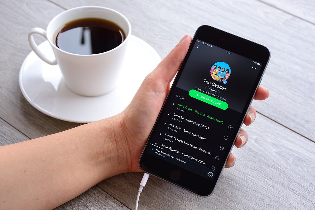 Nazi-Musik via Spotify Hand hält Smartphone, auf dem die Spotify-App läuft