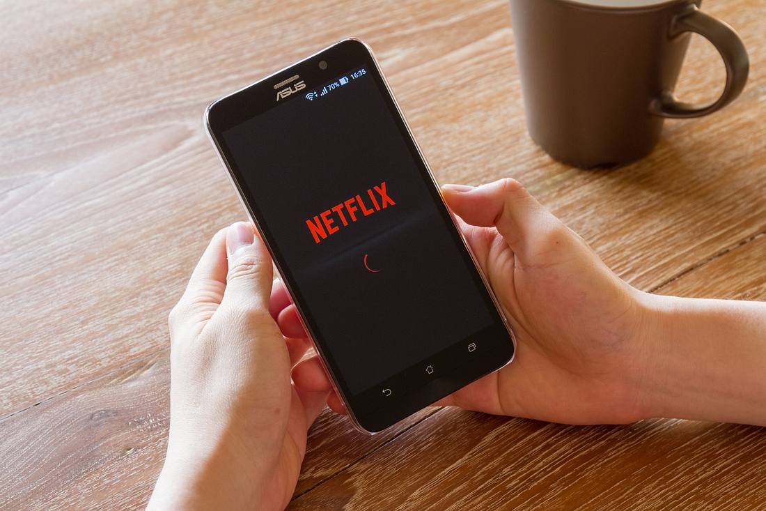 Netflix drosselt Streaming-Qualität in ganz Europa Smartphone mit Netflix-Logo auf dem Bildschirm