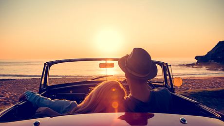 Pärchen im Cabrio bei Sonnenuntergang - Foto: iStock / courtneyk