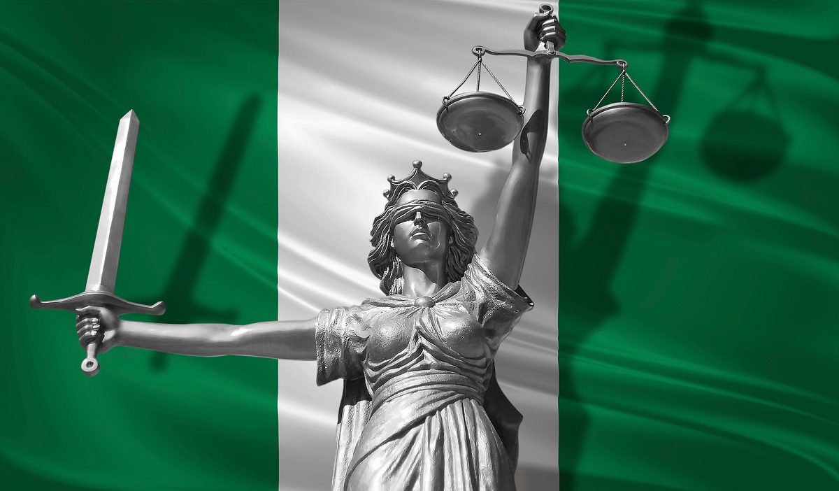 Statue des Gottes der Gerechtigkeit Themis vor der Flagge Nigerias