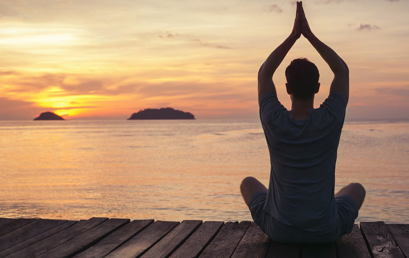 Mann macht Yoga im Sonnenuntergang