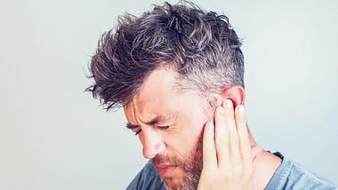 Mann, der sich am Ohr hält - Foto: iStock / Aleksej Sarifulin
