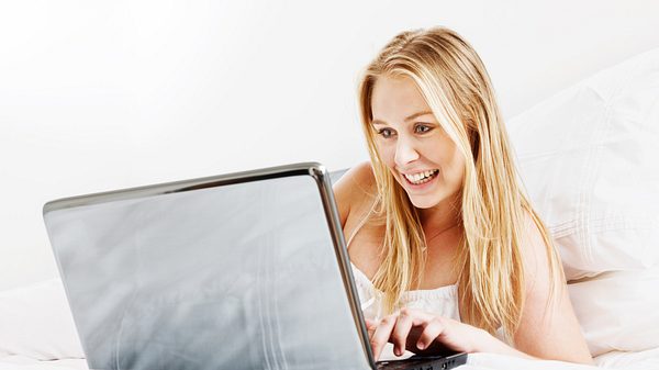 Frau im Bett vor Laptop - Foto: iStock/RapidEye