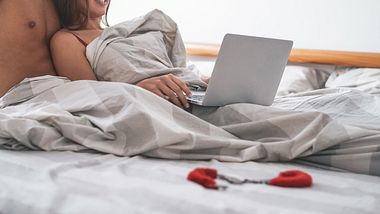 Paar liegt mit Laptop im Bett - Foto: iStock / Alessandro Biascioli
