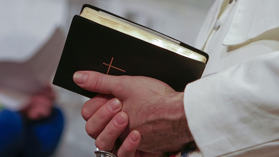 Ein Priester hält ein Gebetbuch 