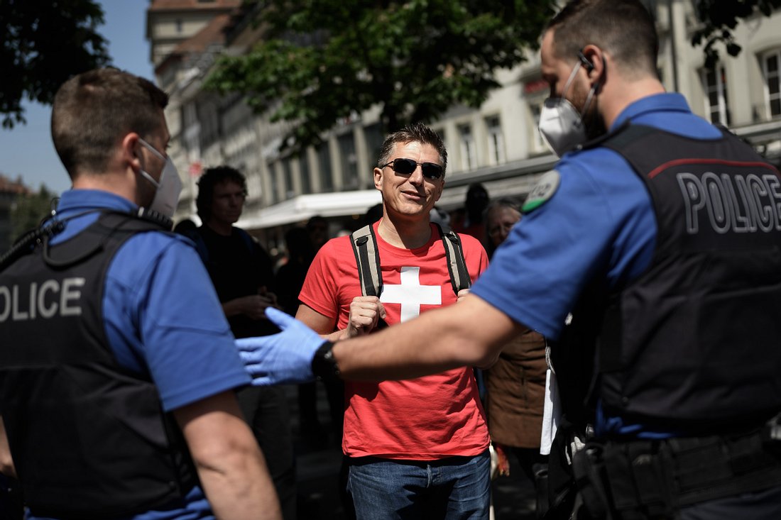Proteste gegen Corona-Beschränkungen in der Schweiz Mann mit Schweiz-Shirt vor Polizisten