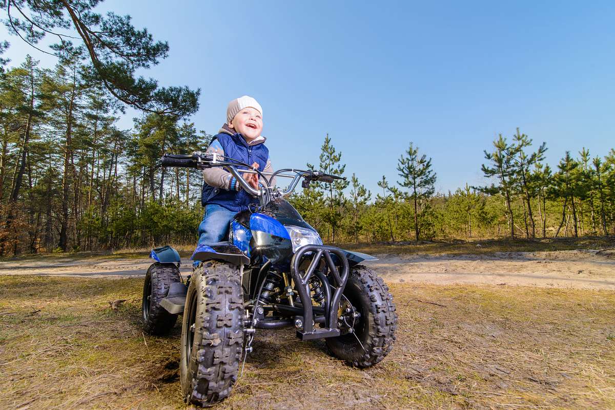 Ein kleiner Junge auf einem Quad für Kinder in der Natur