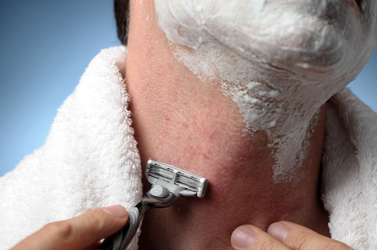 Mann rasiert sich mit einem Nassrasierer