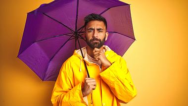 Herr mit Regenjacke und Regenschirm - Foto: iStock/AaronAmat
