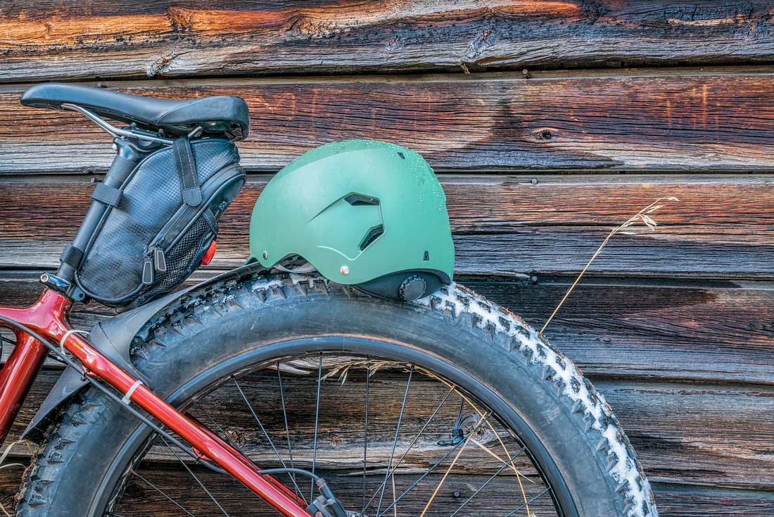 Ein Fahrrad mit Satteltasche steht an eine Holzwand gelehnt