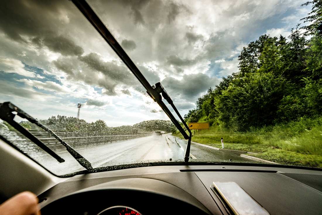 Blick aus der Frontscheibe eines Autos mit Scheibenwischer bei Regen