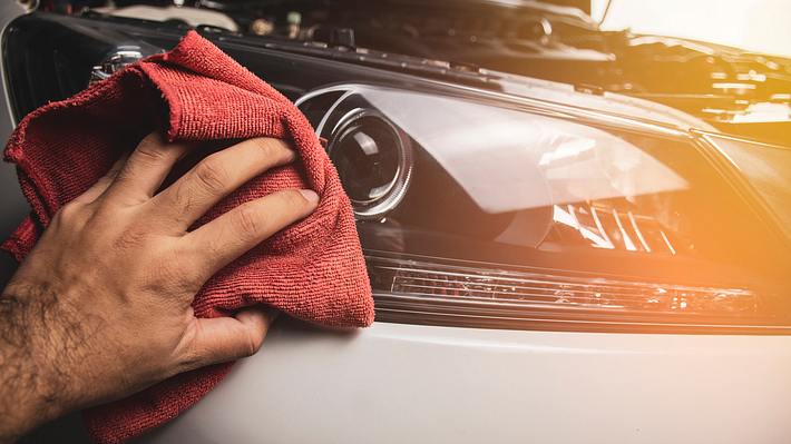 Mann nutzt Produkt für Scheinwerfer-Reparatur - Foto: iStock/Birdlkportfolio