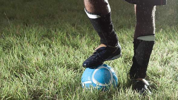 Ein Mann mit einem Fußball und Schienbeinschonern auf dem Rasen - Foto: iStock/edenexposed