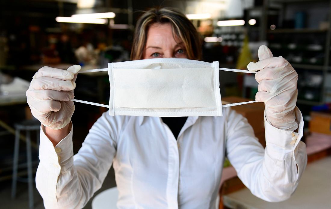 Schutzmasken Frau hält Schutzmaske hoch