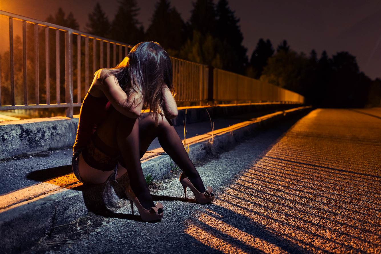 Prostituierte sitzt verzweifelt auf Kantstein