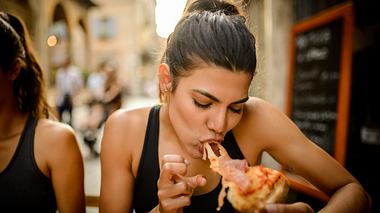 Junge Frau isst Pizza - Foto: iStock / MStudioImages