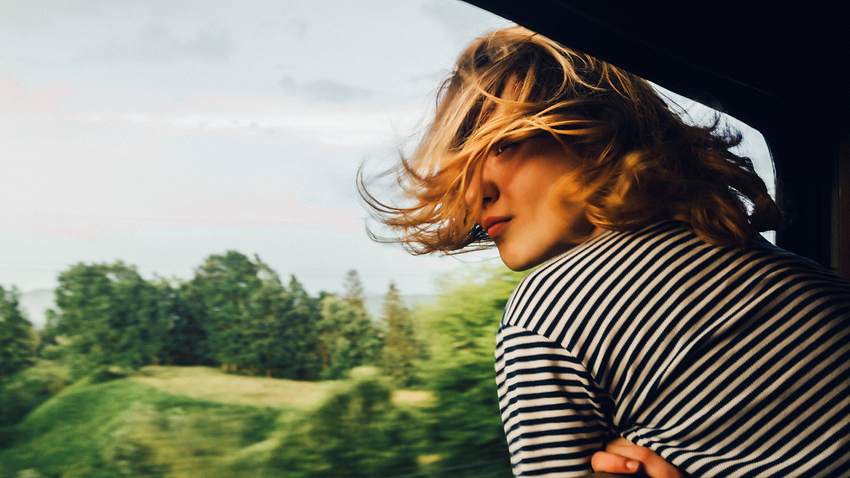 Frau guckt aus dem Zugfenster - Foto: iStock/Oleh_Slobodeniuk