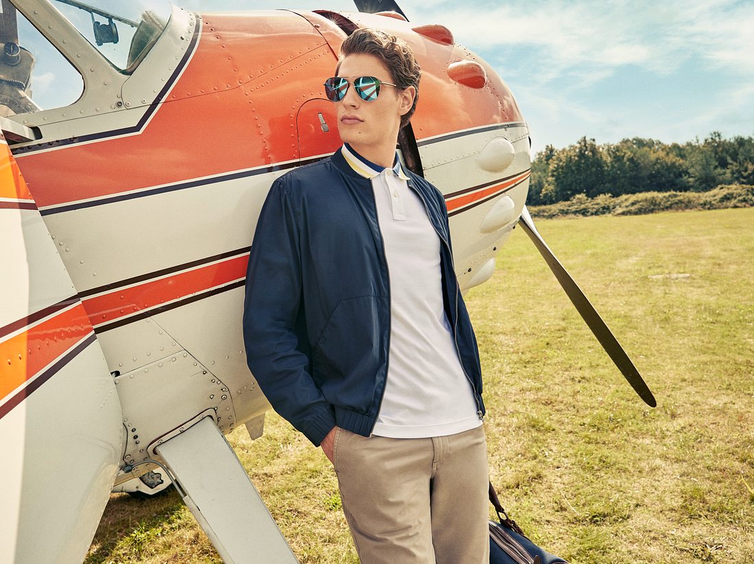 Sonnenbrillentrends 2022 Herren Mann mit Sonnenbrille an ein Flugzeug gelehnt