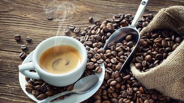 Dampfende Tasse Kaffee, mit einem offenen Sack Kaffeebohnen - Foto: Getty Images / AlexRaths