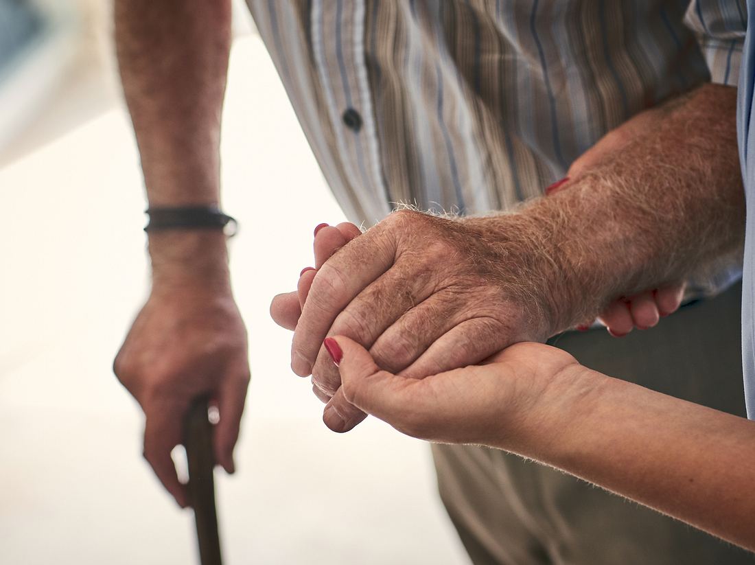 Frau hält älterem Mann die Hand 