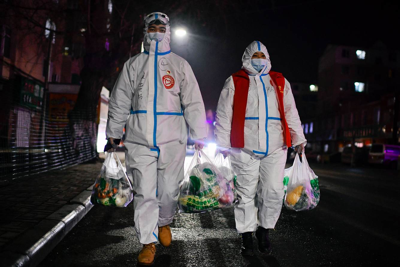 Helfer in Tonghua Menschen in Schutzanzügen und mit Einkaufstüten