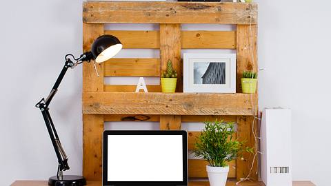 Schreibtisch mit Laptop, Holzpaletten und weiteren Utensilien - Foto: iStock / kinemero