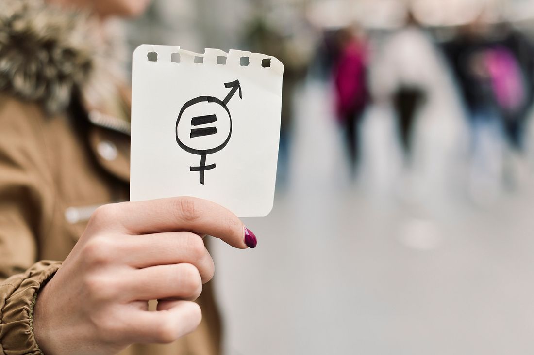 Historische Meilensteine zum Weltfrauentag Frau zeigt Gleichberechtigungsschild