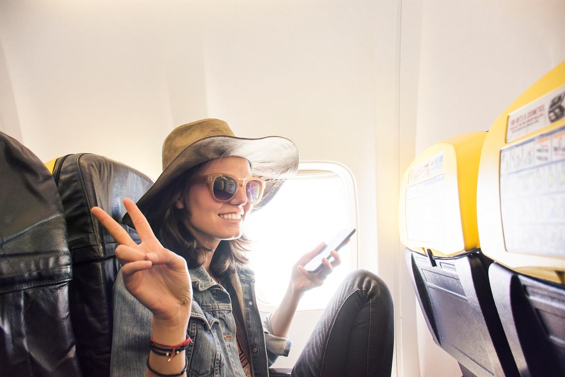 Wenn ich sterbe, sterbe ich: Wie junge Leute wegen Corona billig auf Reisen gehen Jugendliche mit Hut und Sonnenbrille im Flugzeug macht Peace-Zeichen