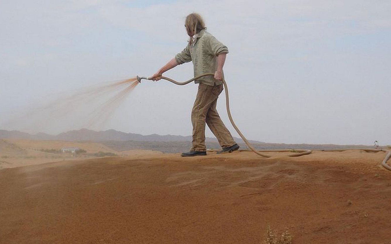 Mann sprüht Nanoton auf Wüstenboden