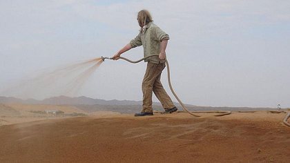 Mann sprüht Nanoton auf Wüstenboden - Foto: Desert Control