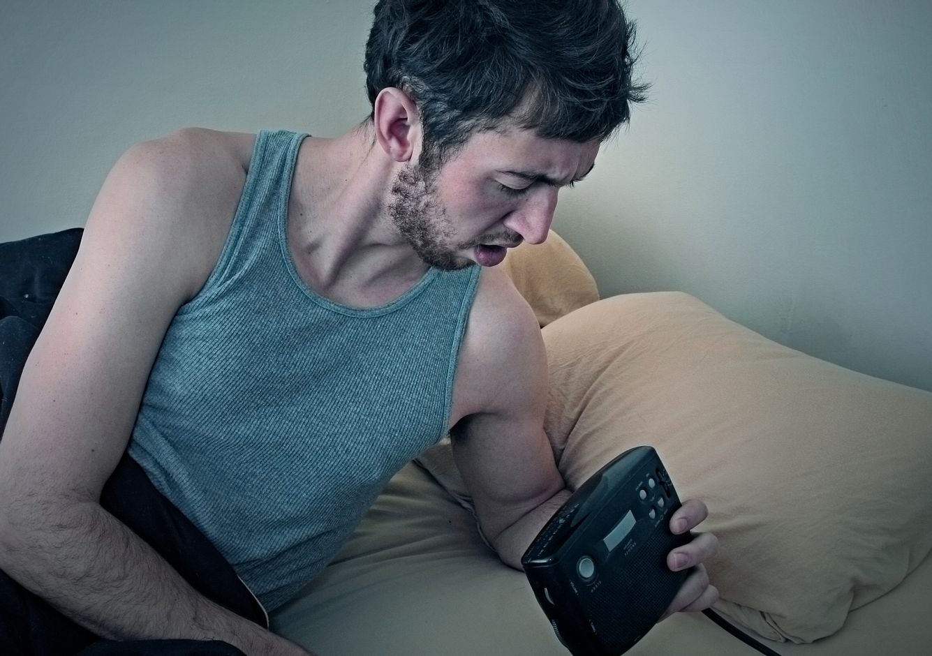 Mann im Bett mit Wecker